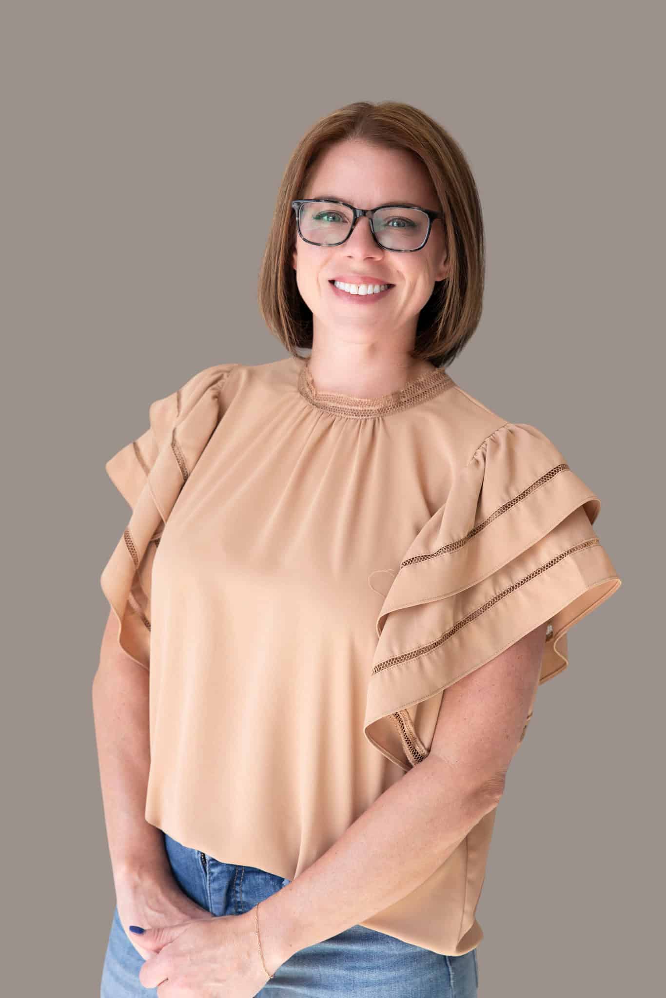 Kaitlin McMillan with short brown hair and glasses smiling.
